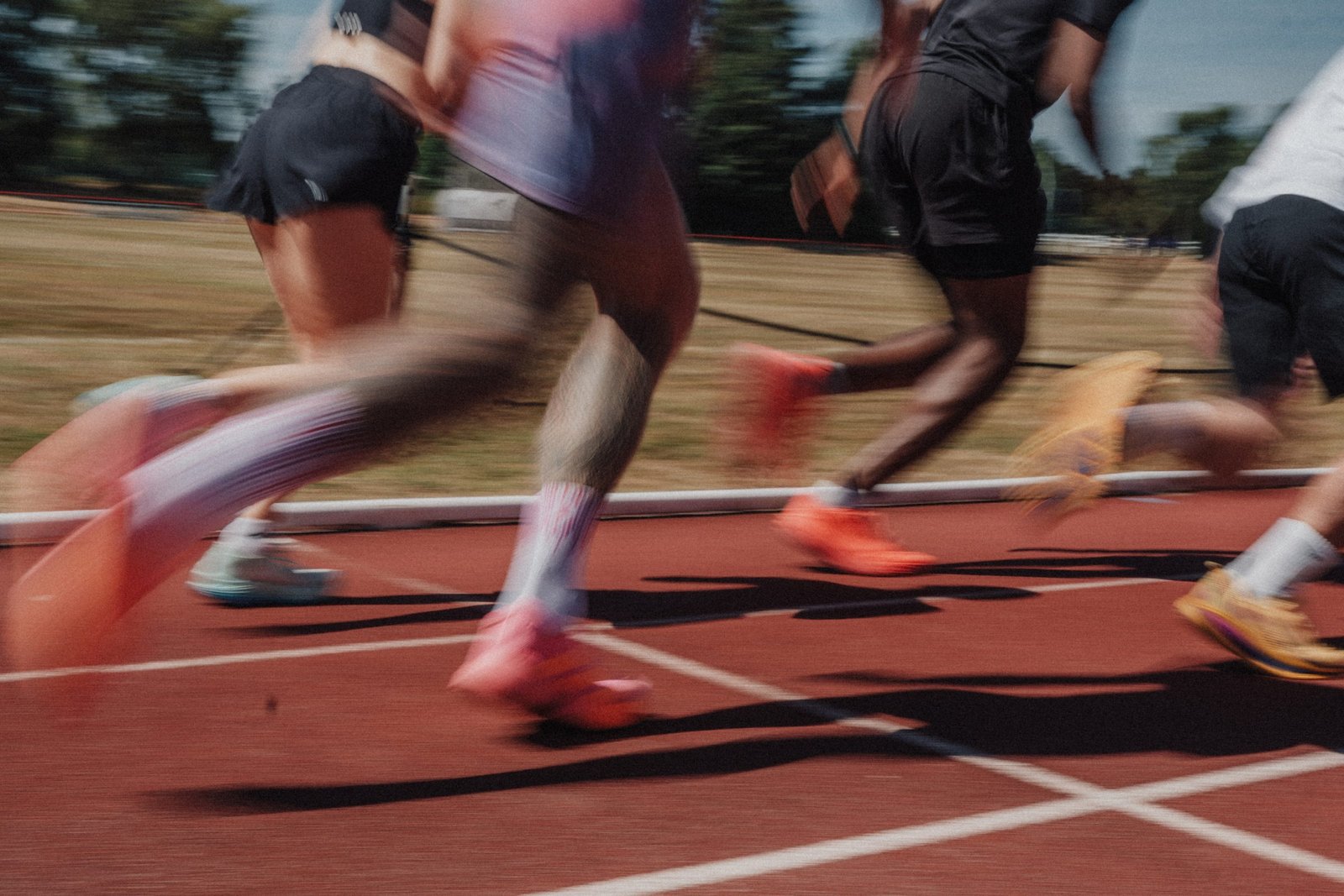 Runners' legs and feet mid-stride on an outdoor track